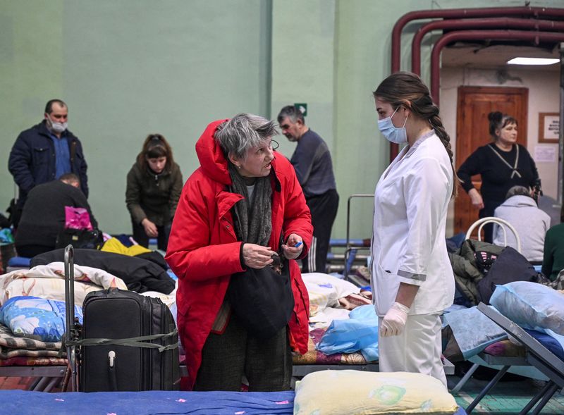 &copy; Reuters. امرأة تم ترحيلها من ماريوبول إلى ملجأ مؤقت في روسيا تتحدث إلى احدى العاملات بالرعاية الصحية في روستوف يوم 23 مارس اذار 2022. تصوير: سيرجي بيفوفا