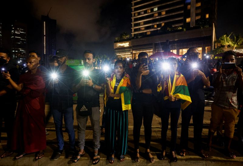 © Reuters. Demonstrators flash flashlights during a candlelight vigil after Sri Lankan police fired live ammunition to scatter protesters killing one person and injuring a dozen more, near the Presidential Secretariat, amid the country's economic crisis, in Colombo, Sri Lanka, April 19, 2022. REUTERS/Navesh Chitrakar