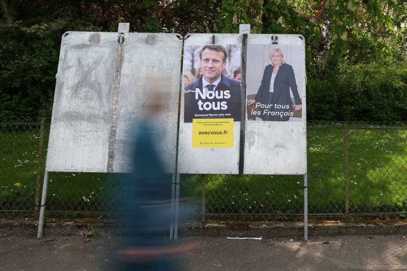 &copy; Reuters. Una mujer pasa por delante de los carteles oficiales de la campaña de los candidatos a las elecciones presidenciales francesas Marine le Pen, líder del partido francés de extrema derecha Agrupación Nacional (Rassemblement National) , y el presidente f