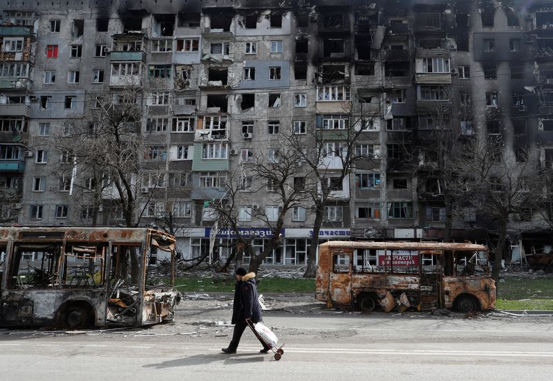 © Reuters. A local resident walks along a street past burnt out buses during Ukraine-Russia conflict in the southern port city of Mariupol, Ukraine April 19, 2022. REUTERS/Alexander Ermochenko