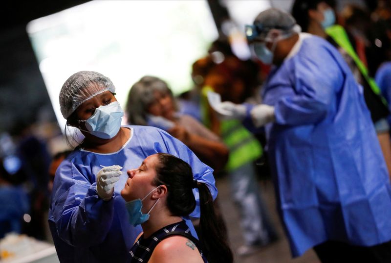 &copy; Reuters. FILE PHOTO: A healthcare worker takes a swab sample from a woman to be tested for the coronavirus disease (COVID-19), at La Rural, in Buenos Aires, Argentina December 23, 2021. Picture taken December 23, 2021. REUTERS/Agustin Marcarian