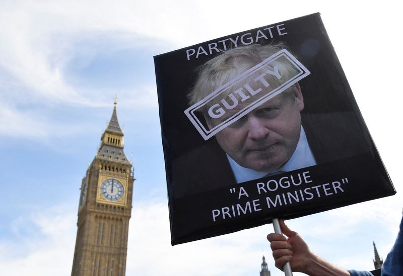 &copy; Reuters. A protestor holds a placard near the Houses of Parliament as British Prime Minister Boris Johnson attends the weekly question time debate at the House of Commons, in London, Britain, April 20, 2022. REUTERS/Toby Melville