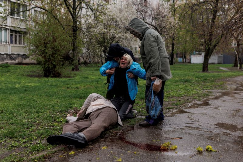 &copy; Reuters. Yana Bachek is consoled by her partner Yevgeniy Vlasenko and her mother Lyubov Gubareva, as she mourns over the body of her father Victor Gubarev, 79, killed by shelling during Russia's invasion of Ukraine, in Kharkiv, Ukraine, April 18, 2022. REUTERS/Alk