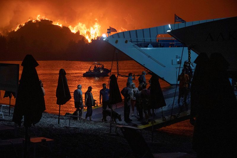 &copy; Reuters. FILE PHOTO: People board a ferry during evacuation as a wildfire burns in the village of Limni, on the island of Evia, Greece, August 6, 2021. REUTERS/Nicolas Economou/File Photo
