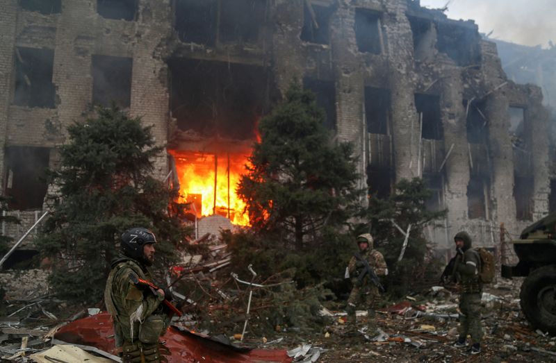 © Reuters. Miembros de las tropas del servicio proruso permanecen frente a un edificio destruído en Mariúpol, Ucrania, 21 de abril del 2022. REUTERS/Chingis Kondarov   