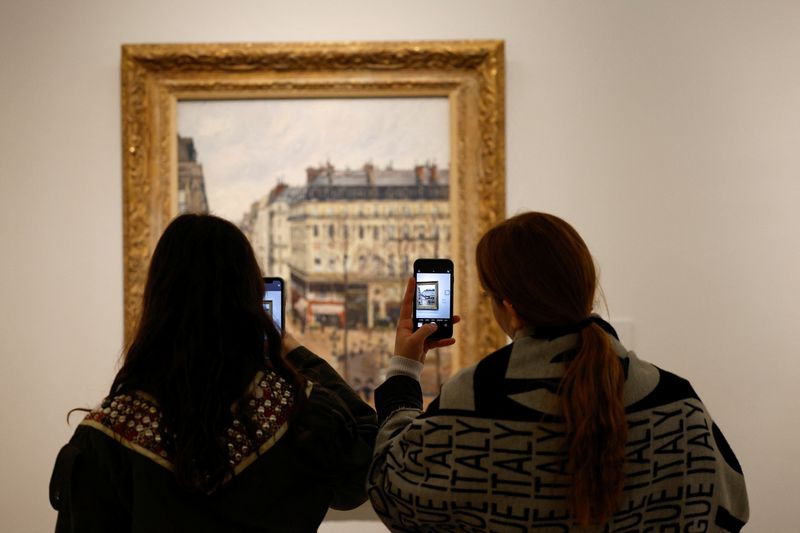 &copy; Reuters. Visitantes fotografían la obra de Camille Pissarro "Rue Saint-Honoré, après-midi. Effet de Pluie, 1897" en el museo Thyssen-Bornemisza de Madrid, España. 22 de abril de 2022. REUTERS/Susana Vera