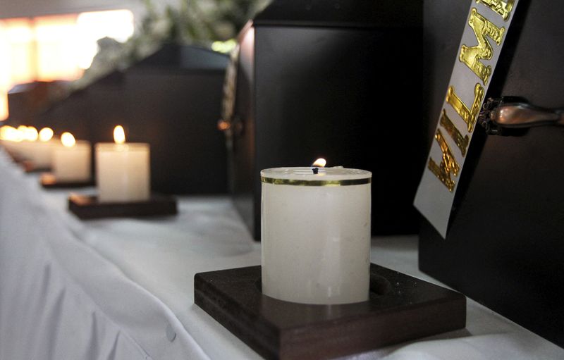 © Reuters. Velas acesas em frente a caixões contendo restos humanos durante cerimônia em Medellín, Colômbia 
26/02/2016
REUTERS/Fredy Builes/File Photo