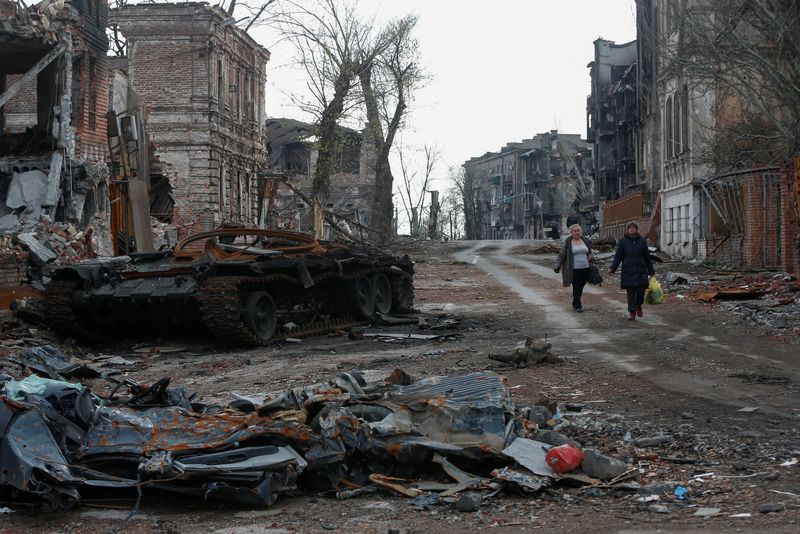 &copy; Reuters. People walk near a destroyed tank and damaged buildings in the course of Ukraine-Russia conflict in the southern port city of Mariupol, Ukraine April 22, 2022. REUTERS/Alexander Ermochenko