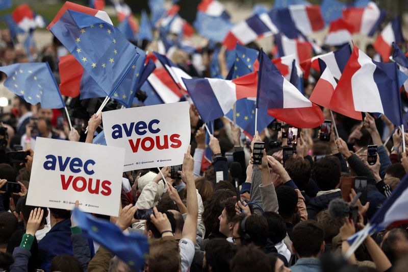 &copy; Reuters. Supporters of French President Emmanuel Macron, candidate for his re-election, wave French and European Union flags as they react after  early results in the second round of the 2022 French presidential election, at the Champs de Mars in Paris, France Apr