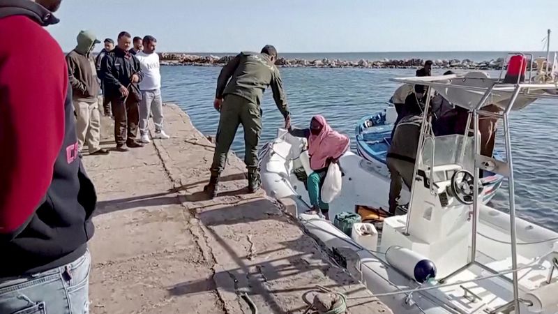 © Reuters. خفر السواحل الوطني التونسي يساعد مهاجرة للصعود إلى الرصيف من زورق انقاذ في صفاقس يوم السبت. صورة لرويترز. 