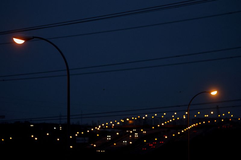 &copy; Reuters. Road lamp posts are seen next to high-voltage power lines as cars drive at dusk in the outskirts of Madrid, Spain, March 28, 2022. Picture taken March 28, 2022. REUTERS/Susana Vera