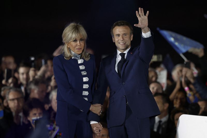 © Reuters. French President Emmanuel Macron waves on stage next to his wife, French first lady Brigitte Macron,  after being re-elected as president, following the results in the second round of the 2022 French presidential election, during his victory rally at the Champ de Mars in Paris, France, April 24, 2022. REUTERS/Benoit Tessier