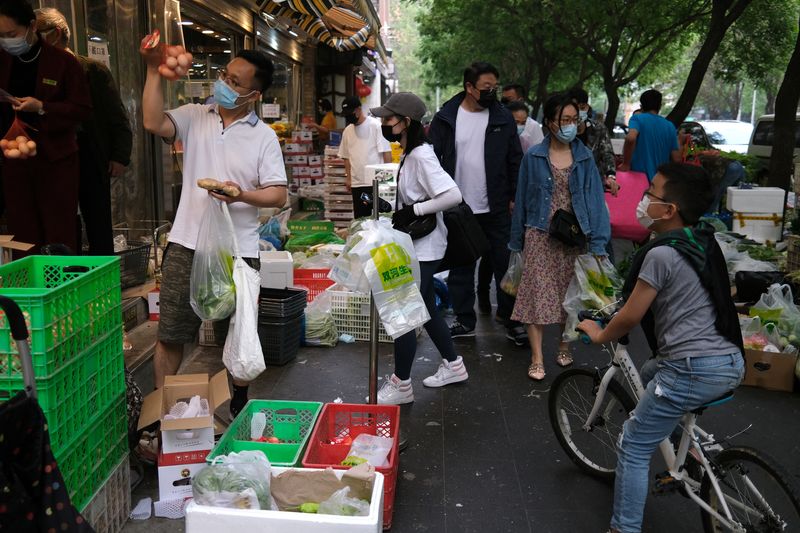 © Reuters. People wearing protective masks buy vegetables from stalls that displayed outside a shop, following the coronavirus disease (COVID-19) outbreak, in Beijing, China April 25, 2022. REUTERS/Tingshu Wang
