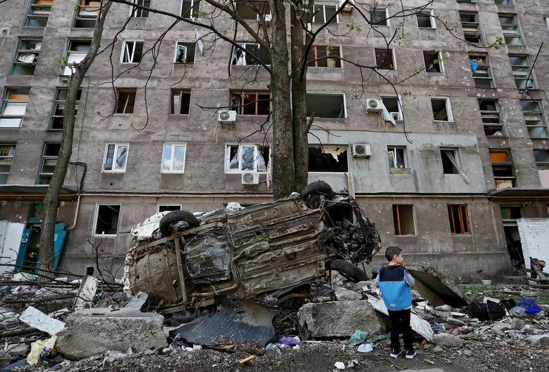 &copy; Reuters. FILE PHOTO: A boy stands next to a wrecked vehicle in front of an apartment building damaged during Ukraine-Russia conflict in the southern port city of Mariupol, Ukraine April 24, 2022. REUTERS/Alexander Ermochenko