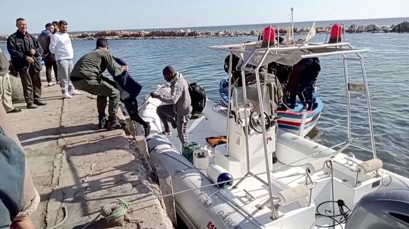 © Reuters. أحد أفراد خفر السواحل التونسي يساعد طفلا من المهاجرين للخروج من قارب انقاذ على ساحل صفاقس يوم السبت. صورة لرويترز من مقطع فيديو التقطة وحيد الداهش.