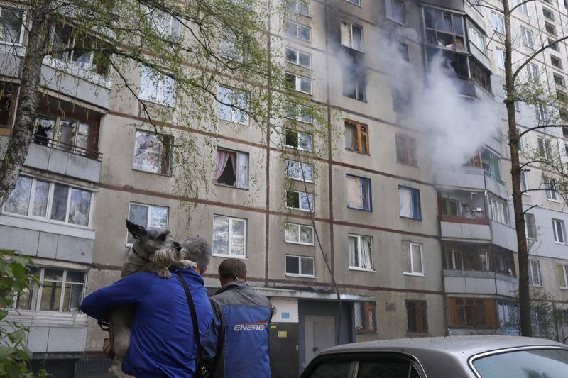 &copy; Reuters. شخصان يسيران أمام مبنى سكني محترق في خاركيف يوم الاثنين عقب قصف روسي. تصوير: ريكاردو مورايس-رويترز.