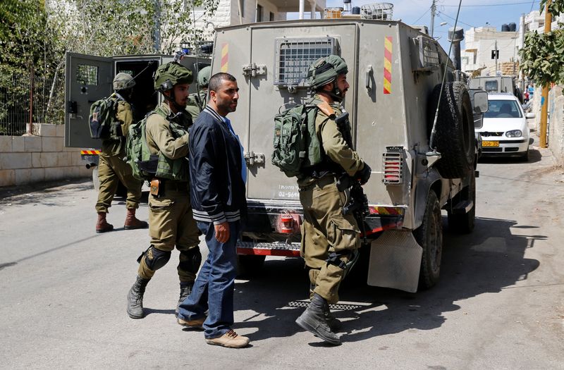 © Reuters. جنود إسرائيليون يعتقلون فلسطينيا قرب مدينة رام الله في الضفة الغربية. صورة من أرشيف رويترز.