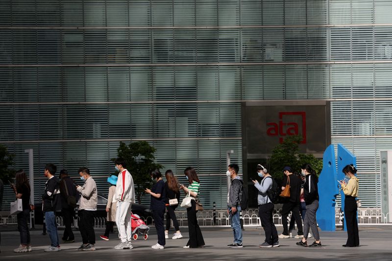 © Reuters. People wearing face masks line up to enter an office building during morning rush hour, following the coronavirus disease (COVID-19) outbreak, in Beijing, China April 26, 2022. REUTERS/Tingshu Wang