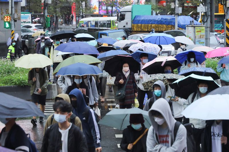 &copy; Reuters. FILE PHOTO: People wearing face masks to prevent the spread of the coronavirus disease (COVID-19) and carrying umbrellas walk on the street during a rainy day in Taipei, Taiwan, November 26, 2021. REUTERS/Annabelle Chih