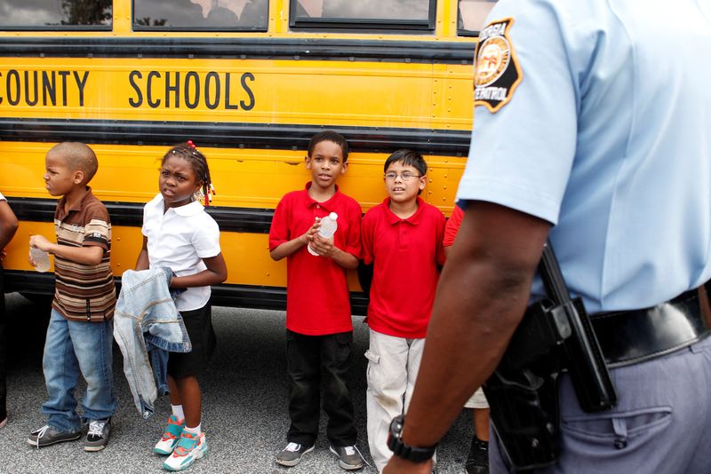 © Reuters. FILE PHOTO: Children stand outside of their school bus in Decatur, Georgia, August 20, 2013./File Photo