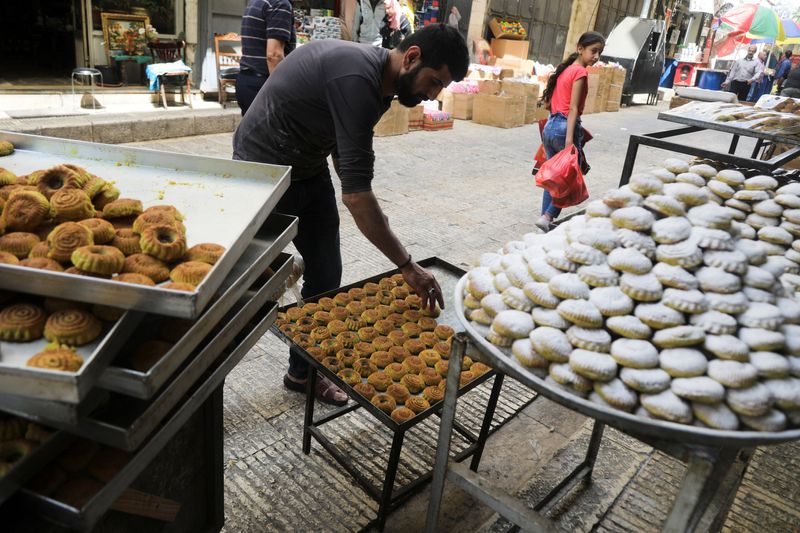 &copy; Reuters. الفلسطيني علاء أبو رميلة يعرض كعك العيد أمام متجر تمتلكه عائلته قبل عيد الفطر في البلدة القديمة بنابلس في الضفة الغربية المحتلة يوم 27 أبريل 