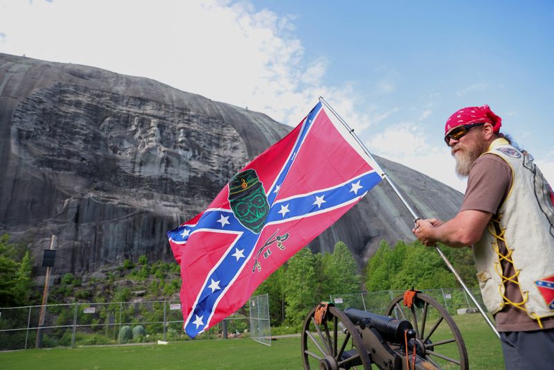 © Reuters. A man holds a confederate flag with a skull on it during Confederate Memorial Day at Stone Mountain Park in Stone Mountain, Georgia, U.S. April 30, 2022.  REUTERS/Dustin Chambers