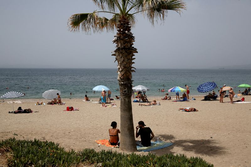 &copy; Reuters. FILE PHOTO: People spend time on the beach during a heatwave in Alimos suburb, south of Athens, Greece July 1, 2021. REUTERS/Costas Baltas/File Photo