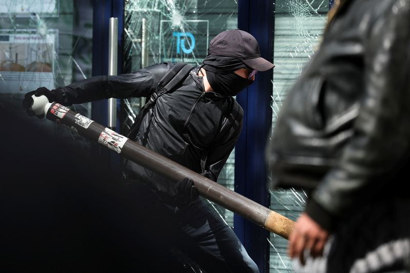 © Reuters. A Black Bloc protestor holds an object next to a broken shop window as the traditional May Day labour union march takes place in Paris, France, May 1, 2022. REUTERS/Sarah Meyssonnier