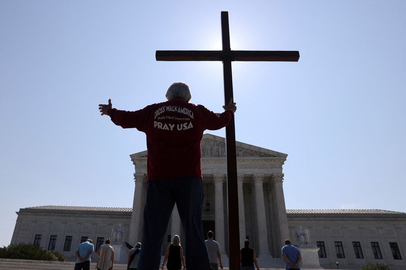 &copy; Reuters. FILE PHOTO: A demonstrators holds a large cross outside the U.S. Supreme Court as the court ruled that religious institutions like churches and schools are shielded from employment discrimination lawsuits in Washington, U.S., July 8, 2020. REUTERS/Jonatha