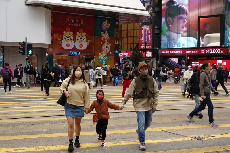 &copy; Reuters. FILE PHOTO: Pedestrians wearing face masks following the coronavirus disease (COVID-19) outbreak cross a street near a mall at Causeway Bay district in Hong Kong, China February 9, 2022. REUTERS/Joyce Zhou/File Photo