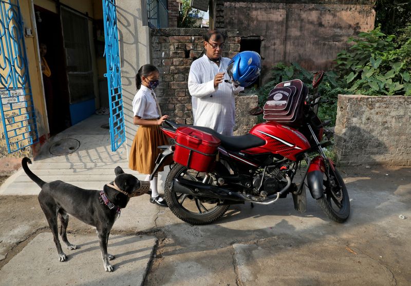 &copy; Reuters. Ambika Chatterjee, 9, a student of fifth grade, who according to her father Subhasish Chatterjee, 52, shifted to a low fee charging private school from an elite school, waits for her father as he puts on his helmet to drop her to a school in Kolkata, Indi