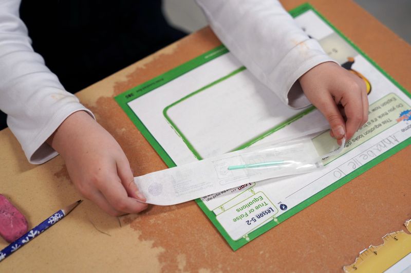 &copy; Reuters. FILE PHOTO: A child opens a testing swab at her desk so she can swab and test herself for COVID-19 to prevent the spread of coronavirus disease (COVID-19) in the classroom at South Boston Catholic Academy in Boston, Massachusetts, U.S., January 28, 2021. 