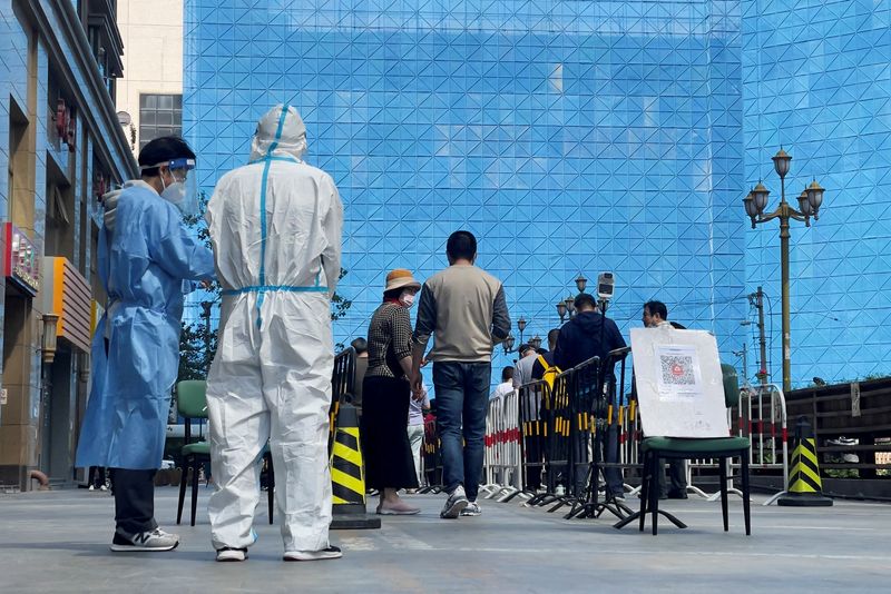 &copy; Reuters. Trabajadores con trajes de protección junto a personas que hacen cola en un lugar improvisado para realizar pruebas de ácido nucleico durante una prueba masiva de la enfermedad del coronavirus (COVID-19) en el distrito de Chaoyang de Pekín, China, el 4
