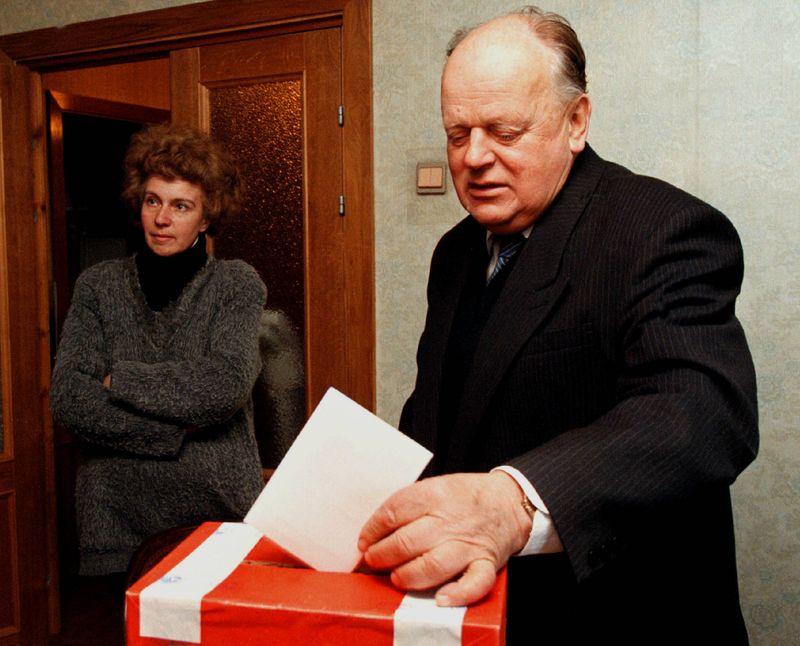 &copy; Reuters. FOTO DE ARCHVO: El exdirigente bielorruso Stanislav Shushkévich introduce un voto en una urna mientras su esposa Irina espera al fondo en su apartamento en Minsk, Bielorrusia, el 13 de mayo de 1999. Fotógrafo de Reuters