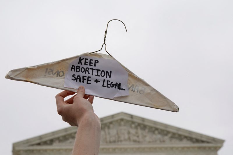 © Reuters. FILE PHOTO: A pro-abortion demonstrator holds up a clothes hanger during a protest outside the U.S. Supreme Court, after the leak of a draft majority opinion written by Justice Samuel Alito preparing for a majority of the court to overturn the landmark Roe v. Wade abortion rights decision later this year, in Washington, U.S. May 3, 2022. REUTERS/Elizabeth Frantz