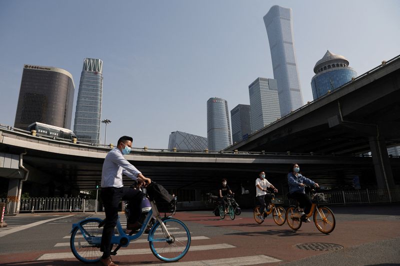 &copy; Reuters. Varias personas con mascarilla circulan en bicicleta durante la hora punta de la mañana por un área de negocios de Pekín, China, el 5 de mayo de 2022. REUTERS/Tingshu Wang  