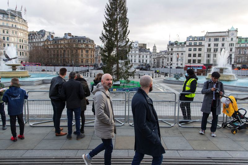 &copy; Reuters. FILE PHOTO: People walk and stand by the temporary fencing around the perimeter of Trafalgar Square, to prevent crowds gathering on New Year's Eve, in London, Britain, December 31, 2021. REUTERS/May James