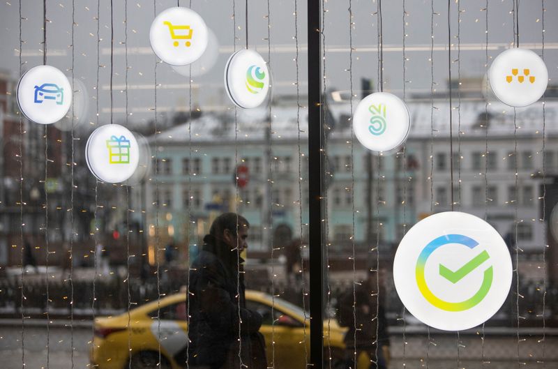 © Reuters. FILE PHOTO: A man walks past an office of the Russian largest lender Sberbank in Moscow, Russia December 24, 2020. The logos of Sberbank ecosystem companies, which launched campaigns and new market, delivery, taxi and online cinema services, are displayed on an office window. REUTERS/Maxim Shemetov