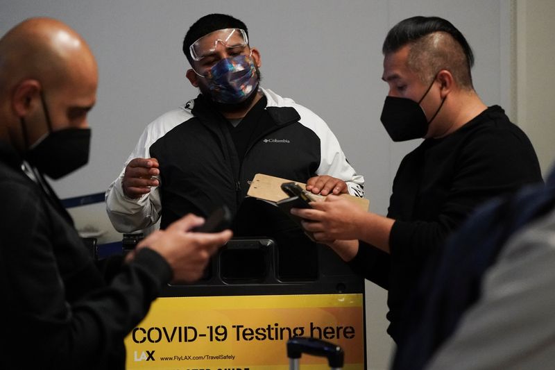 © Reuters. FILE PHOTO: Travelers wait in line to get tests for the coronavirus disease (COVID-19) at a pop-up clinic at Tom Bradley International Terminal at Los Angeles International Airport, California, U.S., December 22, 2021. REUTERS/Bing Guan