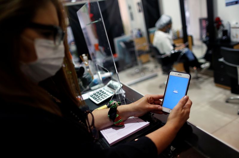 © Reuters. FILE PHOTO: AM hair salon owner, Andrea Manoli, is pictured using Mercado Pago app, at her store in Buenos Aires, Argentina, October 15, 2020. REUTERS/Agustin Marcarian