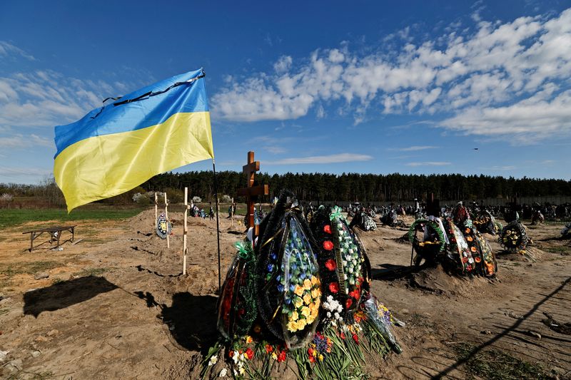 &copy; Reuters. Bandeira da Ucrânia ao lado de covas de pessoas mortas durante invasão da Ucrânia pela Rússia em cemitério na cidade ucraniana de Bucha
28/04/2022 REUTERS/Zohra Bensemra