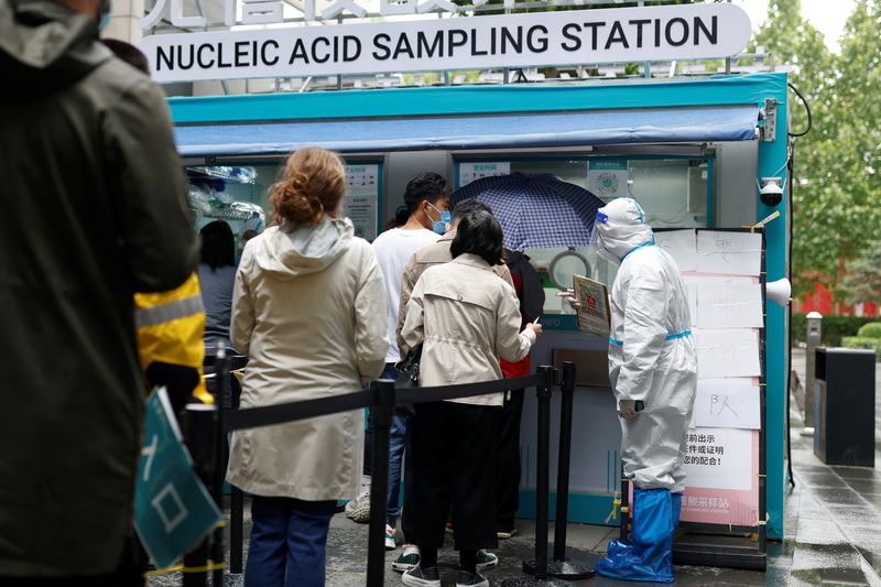 &copy; Reuters. FILE PHOTO: People line up to get tested next to a staff member wearing personal protective equipment (PPE) at a mobile nucleic acid testing site outside a shopping mall, amid the coronavirus disease (COVID-19) outbreak in Beijing, China May 6, 2022. REUT