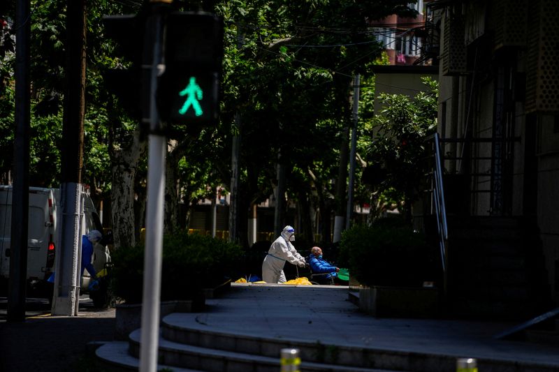 &copy; Reuters. FILE PHOTO: A worker in a protective suit helps an old man with a wheelchair during lockdown amid the coronavirus disease (COVID-19) pandemic, in Shanghai, China, May 5, 2022. REUTERS/Aly Song/File Photo