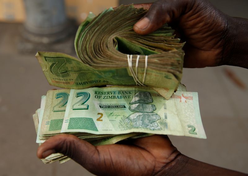 &copy; Reuters. FILE PHOTO: A street vendor poses as he displays bond notes, before the introduction of new currency in Harare, Zimbabwe, November 11,2019. REUTERS/Philimon Bulawayo