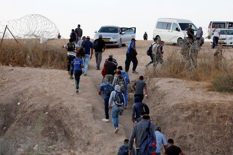 &copy; Reuters. عمال فلسطينيون يعبرون للعمل في إسرائيل من فتحة في سياج بين الضفة الغربية المحتلة وإسرائيل قرب الخليل. صورة من أرشيف رويترز.