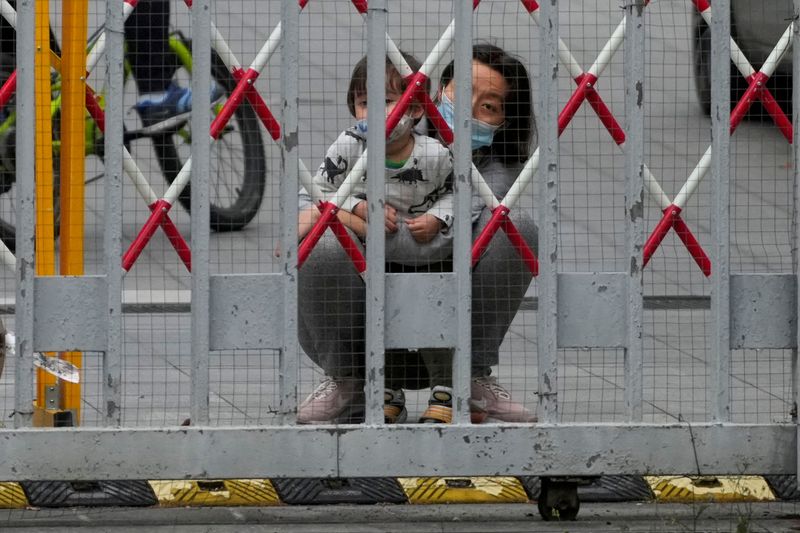 &copy; Reuters. A resident and a child look out through gaps in the barriers at a closed residential area during lockdown, amid the coronavirus disease (COVID-19) pandemic, in Shanghai, China, May 10, 2022. REUTERS/Aly Song   