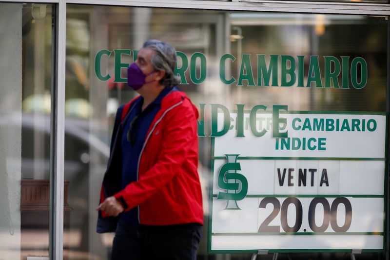 &copy; Reuters. FOTO DE ARCHIVO-Una persona camina junto a una tienda de cambio de divisas con una pantalla del tipo de cambio del dólar estadounidense y el peso mexicano en la Ciudad de México, México, 24 de febrero de 2022. REUTERS/Gustavo Graf