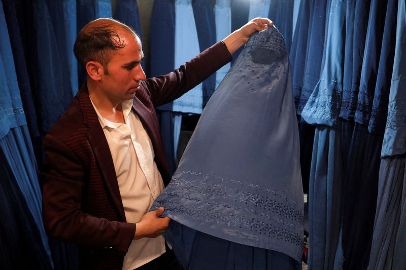 &copy; Reuters. An Afghan salesman displays a burqa in his shop at a marketplace in Kabul, Afghanistan, May 10, 2022. REUTERS/Ali Khara