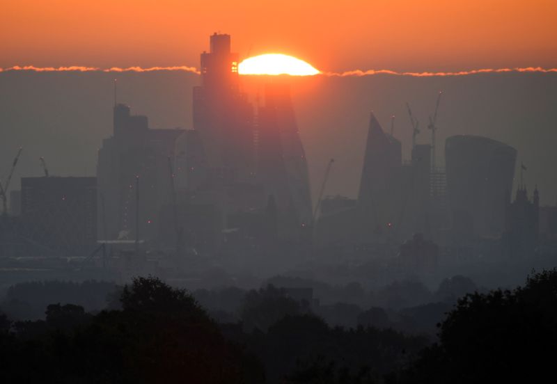 &copy; Reuters. FILE PHOTO: The sun rises behind skyscrapers and offices of the City of London financial district in London, Britain, May 5, 2022. REUTERS/Toby Melville    