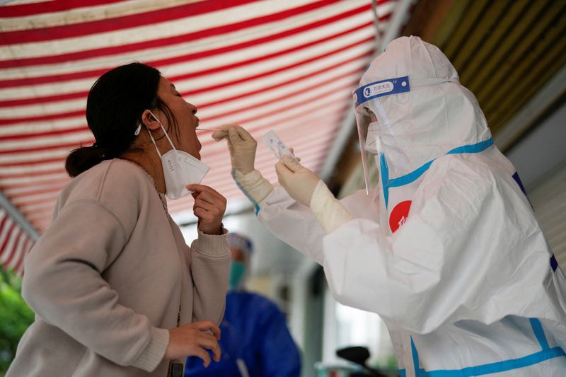 &copy; Reuters. Una trabajadora médica en un traje de protección realiza un hisopado para recolectar muestras de una residente para una prueba de ácido nucleico, afuera de un edificio cerrado durante un confinamiento en medio de la pandemia de COVID-19, en Shanghái, 